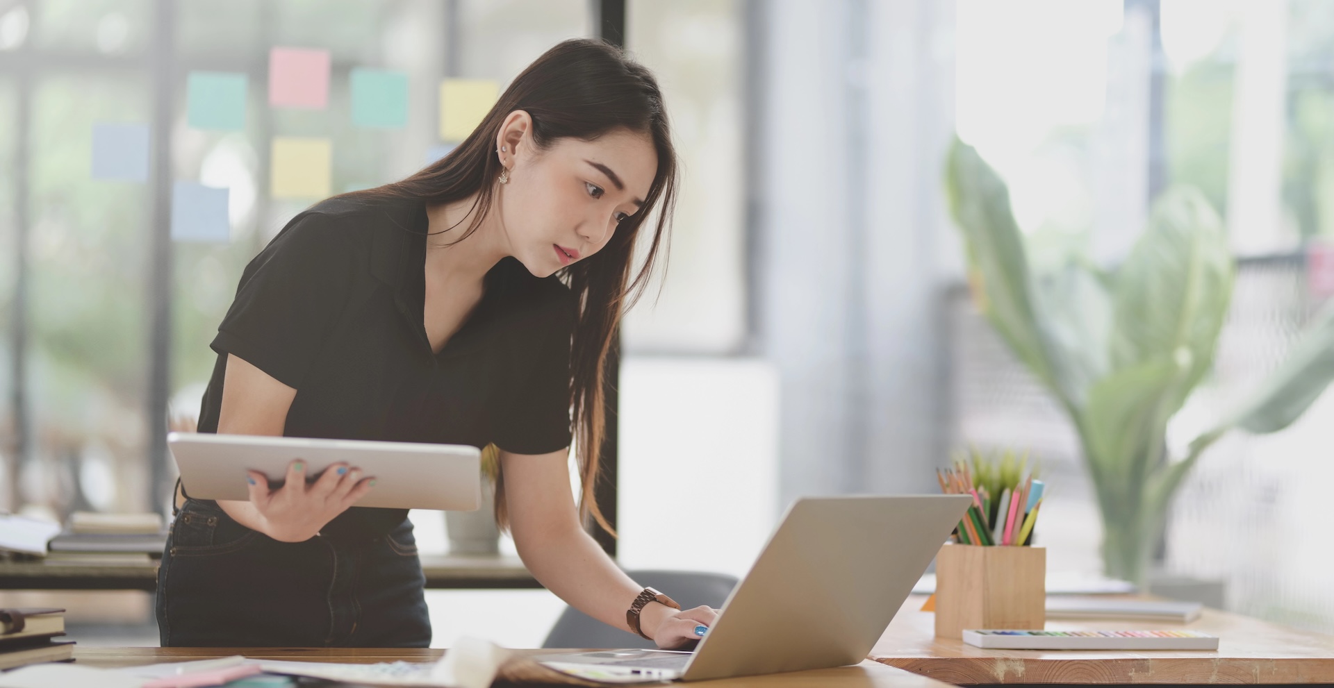 Female freelancer standing at desk looking at laptop screen