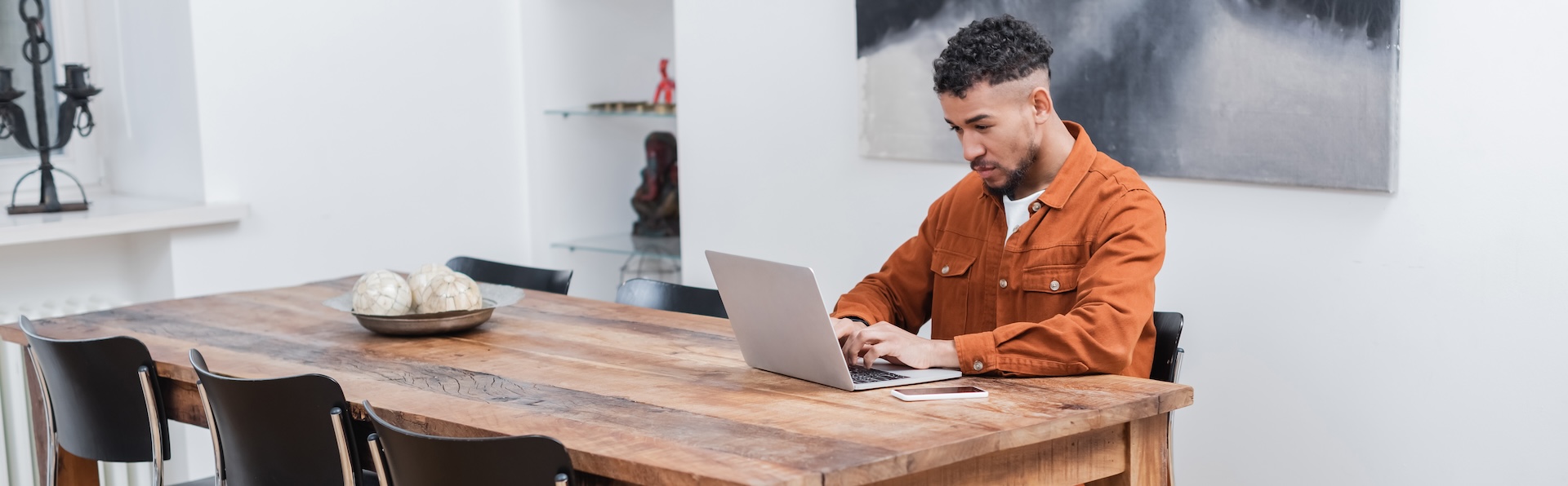 Man working on a laptop at a wooden dining table