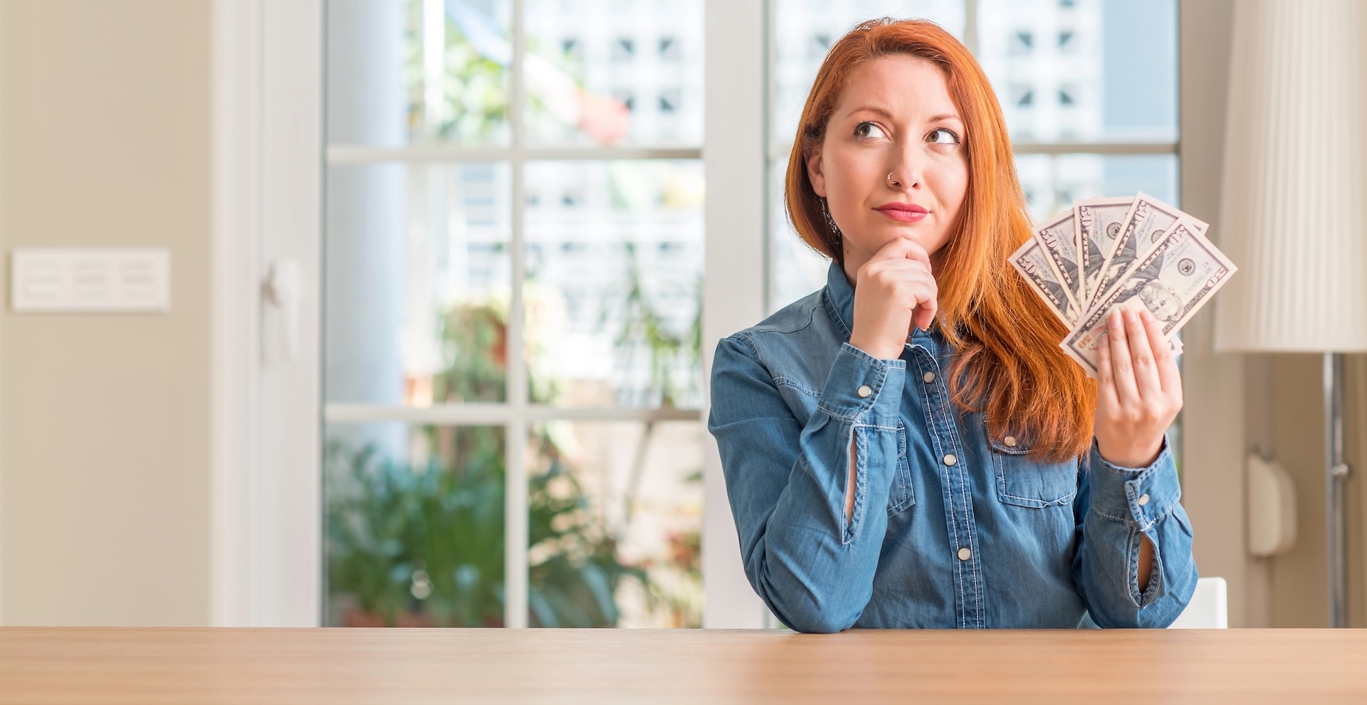 Freelancer siting behind desk holding cash in their hand